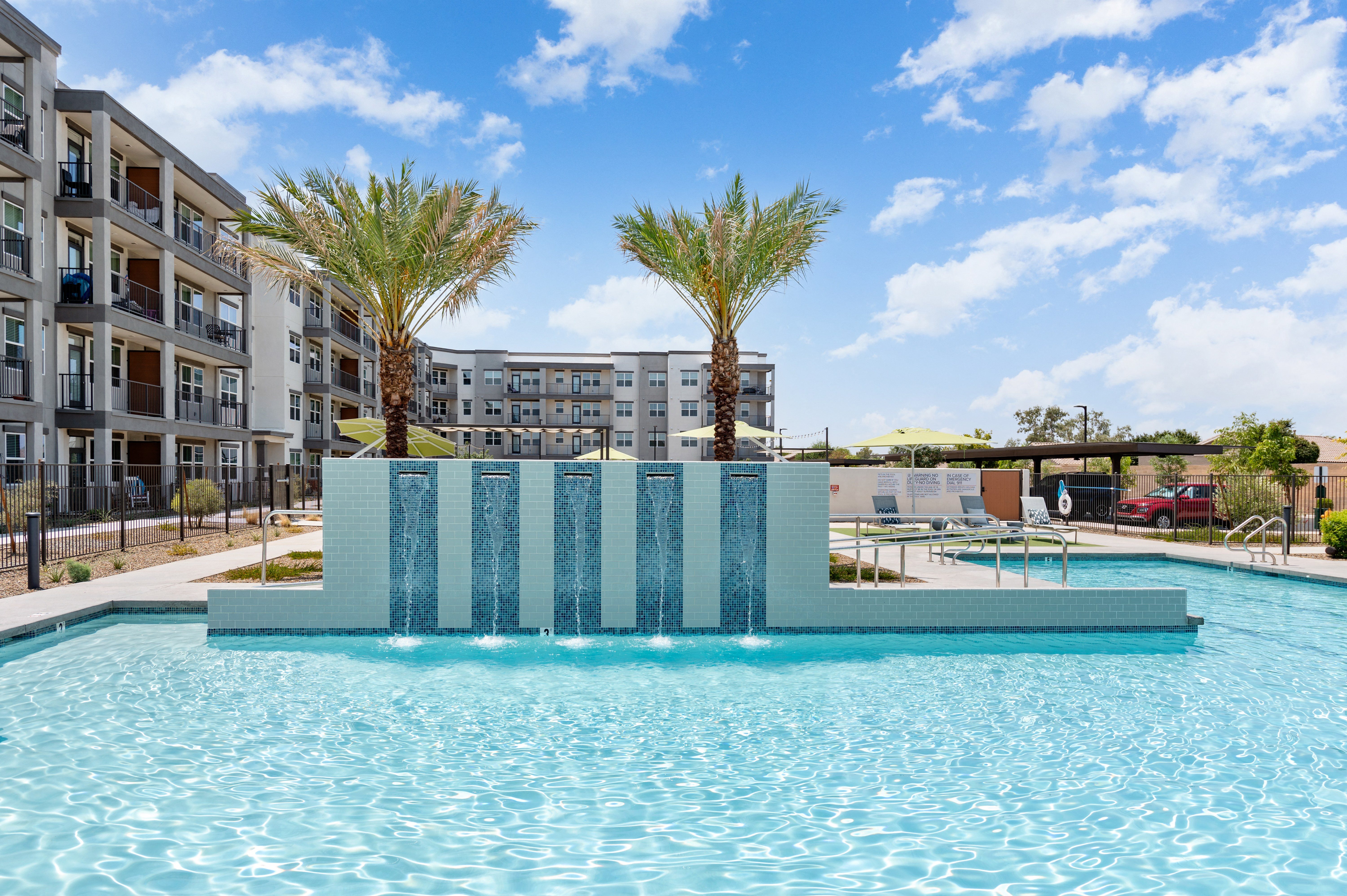 a large pool with palm trees and an apartment building in the background